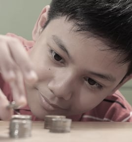 Boy Stacking a Pile of Coins